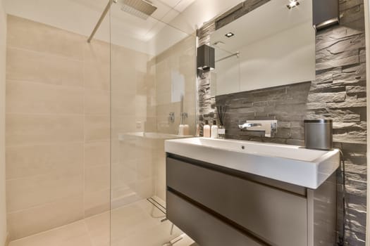 a modern bathroom with grey and white tiles on the walls, shower stall and toilet in the corner of the room