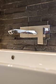 a bathroom sink with a mirror on the wall behind it is a white bathtub and black marble flooring