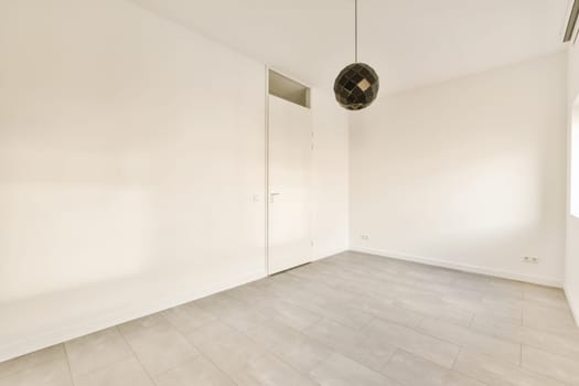 an empty room with white walls and wood flooring, there is a fan on the wall in the corner
