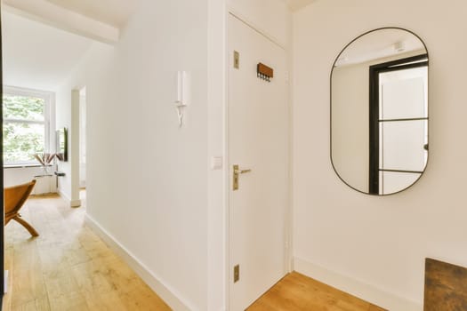 a hallway with a mirror on the wall and a table in the corner next to it, there is an open door that leads