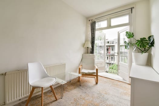 a living room with a chair, rad and a plant in the corner on the wall is painted white