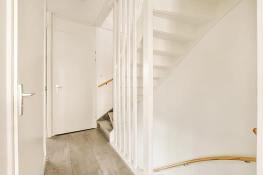 a hallway with white walls and wooden stairs leading up to the second floor in an apartment or residential house interior