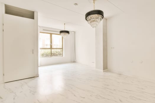 an empty room with white marble flooring and a chandel light hanging from the ceiling over the doorways