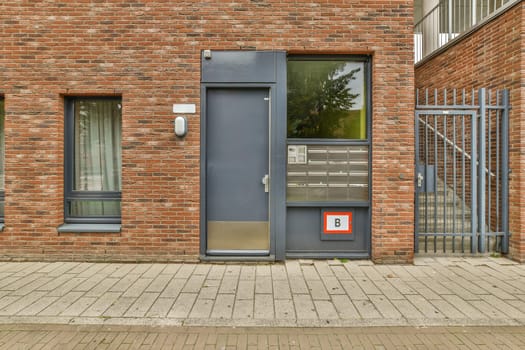 a brick building with an open door on the left side, and two windows in the middle one is closed