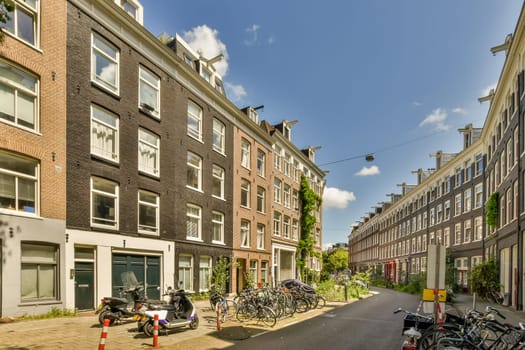 some bikes parked on the side of a street in an urban area with buildings and people walking down the street