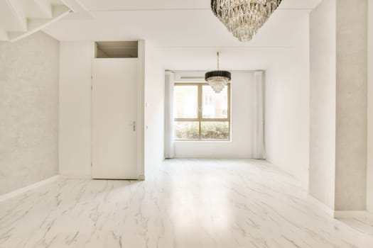 an empty room with white marble flooring and a chandel light fixture hanging from the ceiling over the doorway