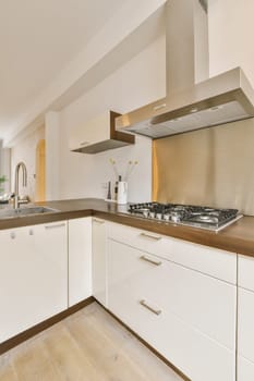 a modern kitchen with white cabinets and wood counter tops in an open plan area for the stove hood is on