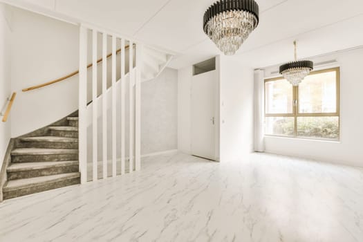 an empty living room with marble flooring and white walls there is a chandel hanging from the ceiling light