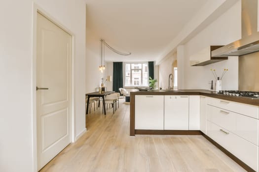 a kitchen and dining area in a house with wood flooring, white cabinets and counters on either sides