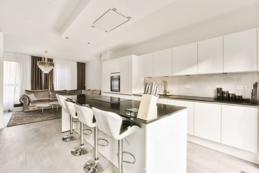 a kitchen and dining area in a modern style apartment with white cabinets, black counter tops and marble flooring