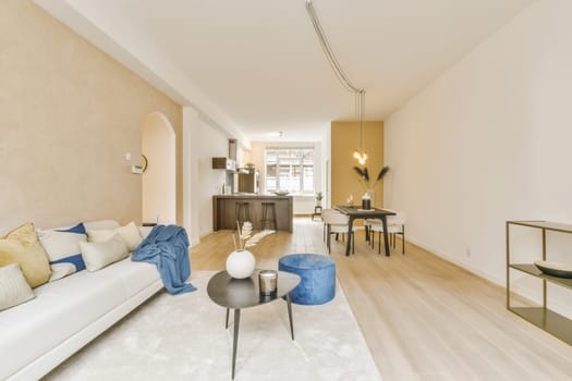 a living room with wood flooring and white couches in the room is decorated with blue throw pillows on it