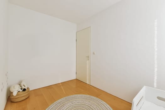 an empty room with white walls and wood flooring, there is a round rug on the floor in front of the door