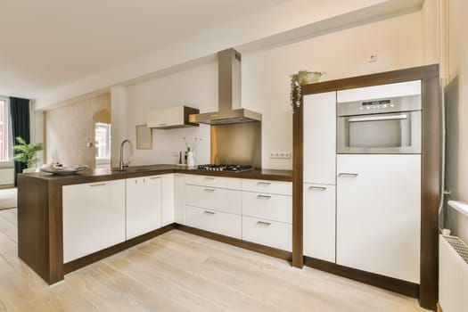 a modern kitchen with white cabinets and wood flooring in the middle part of the image is taken from above