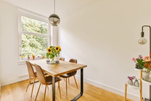 a dining table and chairs in a room with white walls, wood flooring and large windows looking out onto the street