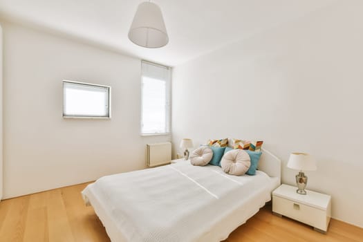a bedroom with white walls and wood flooring the room has a bed, two nightstands and a window