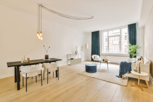a living room with wood flooring and white walls, including a black dining table surrounded by blue drapes