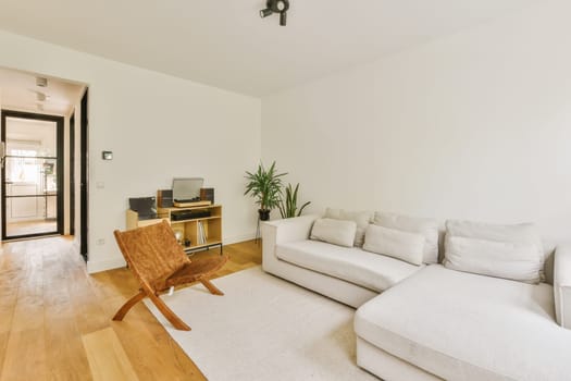 a living room with white couches and wood flooring in the center of the room is an open door
