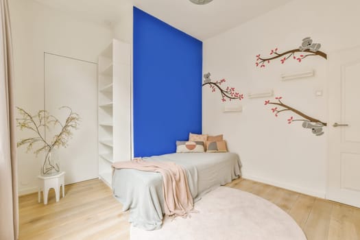a bedroom with blue walls and white furniture on the floor, there is a small bed in front of it