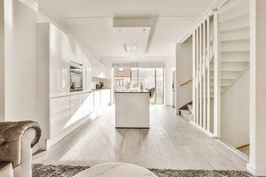 a kitchen and dining area in a house with white cabinets, marble flooring and an open staircase leading to the living room