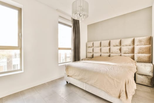 a bedroom with white walls and beige bedding in the middle of the room, there is a chandel on the headboard