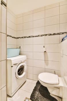 a small bathroom with a toilet and washer in the corner, while it is white tile on the walls