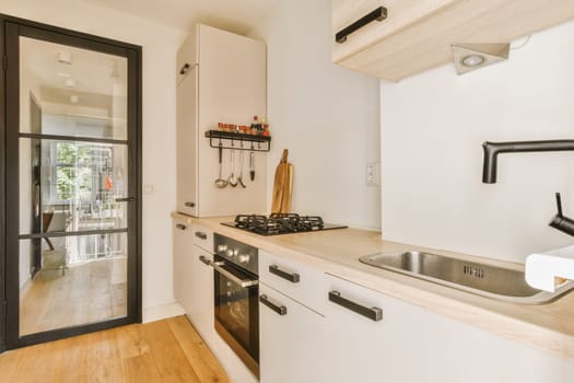 a kitchen with wood flooring and white cupboards, black door handles, and an oven in the corner
