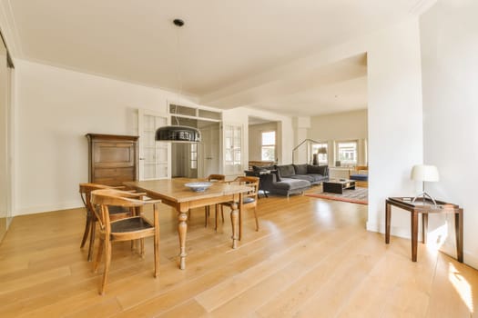 a living room with wood flooring and white walls, including a wooden dining table surrounded by two chairs in the room is empty