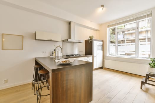 a kitchen and dining area in a house with white walls, hardwood flooring and large windows overlooking out onto the street