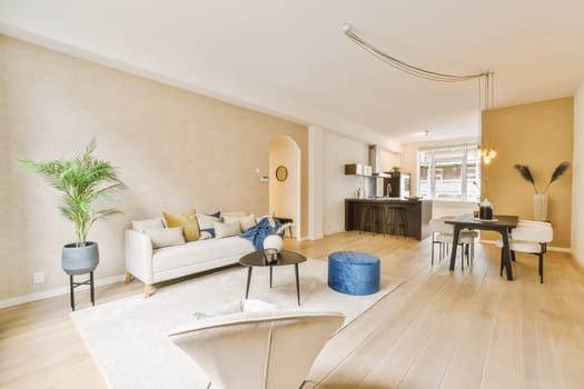 a living room with wood flooring and white furniture in the center of the room is a couch, coffee table, two chairs