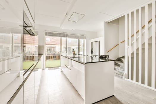 a modern kitchen with white cabinets and black counter tops in the center of the room, there is a glass door that leads to an outdoor patio