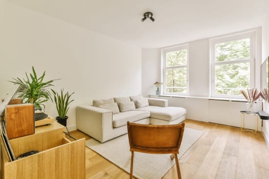 a living room with white walls and hardwood flooring, there is a large window that looks out to the trees outside