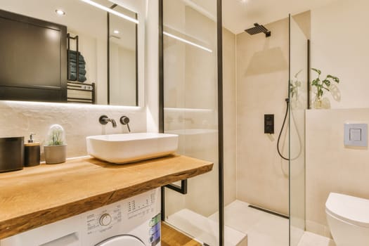 a bathroom with a sink, toilet and washer on the counter in front of the shower stall is made out of wood