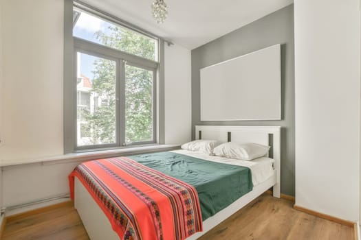 a bedroom with a bed and a large window in the corner that looks out to the trees outside it is bright