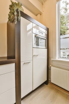 a kitchen with white cabinets and wood flooring in front of a window that looks out to the garden outside