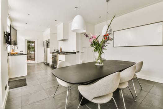 a kitchen and dining area in a house with white walls, grey flooring and black countertops on the wall