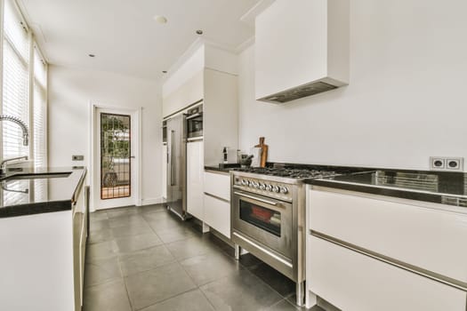 a modern kitchen with white cabinets and black countertops on the island in the center of the room is an open door that leads