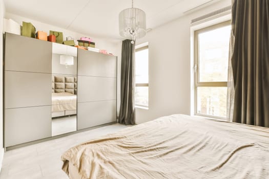 a bedroom with an unmade bed and wardrobes on the wall behind it is a large window that looks out onto the street