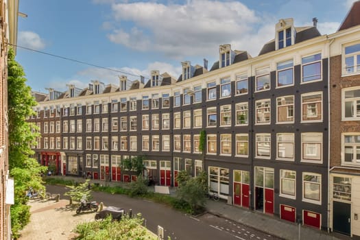 a street in the city with many houses and buildings on either side, one building has red shuttered windows