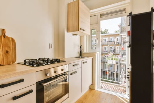 a kitchen with an open door leading to the patio area and outside view through the sliding glass door that leads out onto the balcony