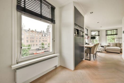 a living room with wood flooring and white walls there is a dining table in front of the large window