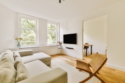 a living room with white walls and hardwood flooring, there is a flat screen tv mounted on the wall