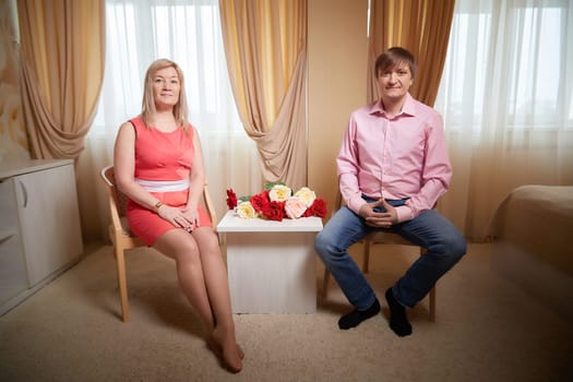 Couple poses together in a hotel room, surrounded by flowers, celebrating love and their special bond.