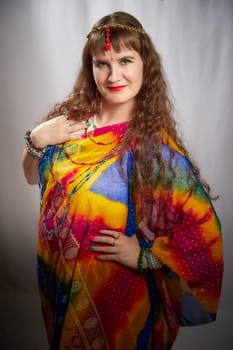 A middle-aged blonde woman showcases her beauty in a vibrant sari during a lifestyle photo shoot, posing with elegance and charm.