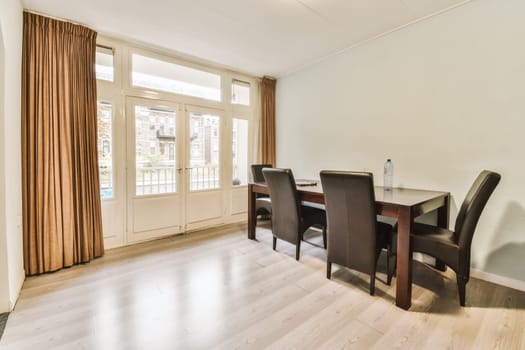 a dining table and chairs in a living room with sliding glass doors leading to the balcony area, which can be used as a