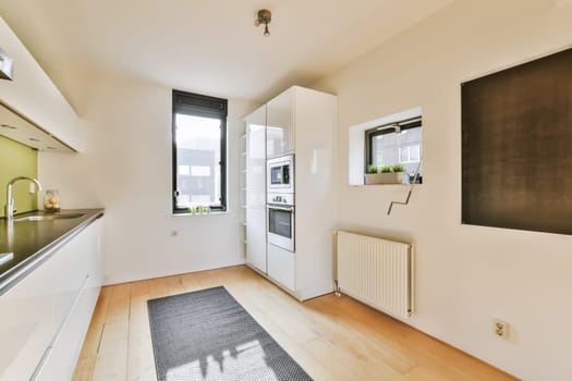 an empty kitchen and dining area in a house with white walls, hardwood flooring and black countertops on the wall