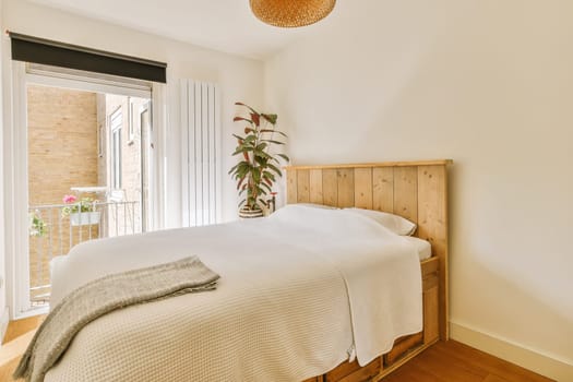 a bedroom with a bed, window and plant in the corner on the right side of the room is bright white walls