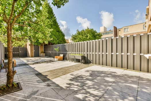 a fenced area with trees and buildings in the background on a sunny day at an urban townhome