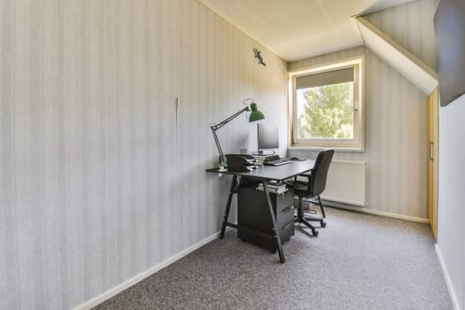 an office space with a desk, chair and computer on the floor in front of a window looking out onto trees