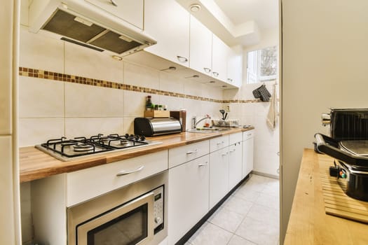 a kitchen with white cupboards and wood counter tops on the counters in this is taken from an open door