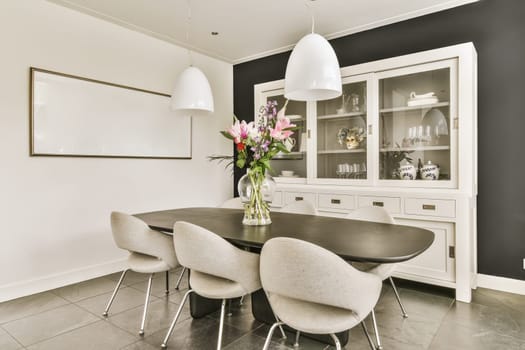 a black and white dining room with flowers in a vase on the table next to two chairs that are facing towardss